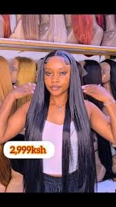 Woman modeling long black straight hair wig in store display with price tag showing 2999ksh