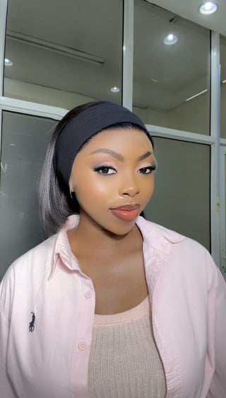 Woman with black headband and sleek hair wearing a light pink button-up shirt