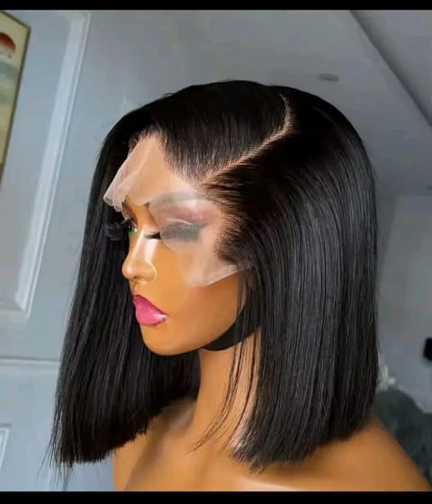 Woman wearing black blunt bob wig with lace front and bold pink lipstick makeup against white background