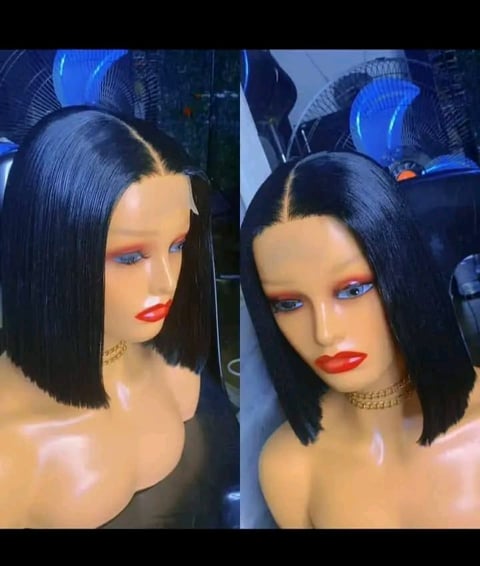 Two mannequin heads displaying black bob wigs with blue eyeshadow, red lipstick, and blue bow accessories